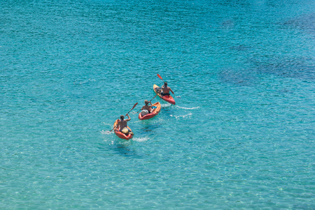 Guys paddling on canoes in the crystal clear seaの写真素材