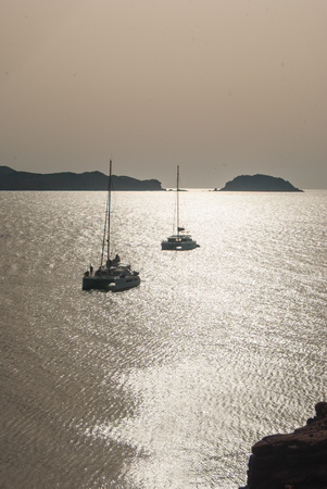 2 fixed catamarans with the promontory of Cavalleria beach in Spain during the sunsetの写真素材