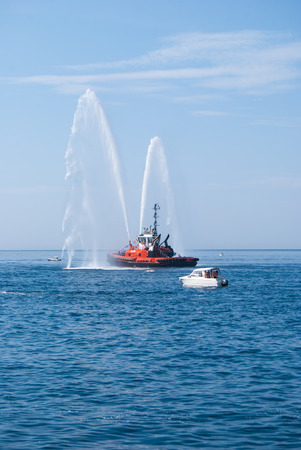 Two jets of sea water sprayed by a fire engine of a firefighters red boatの写真素材