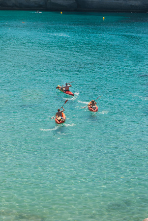 Adults paddling on canoes in the crystal clear seaの写真素材