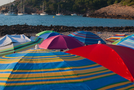 Colorful and striped beach umbrellas in a hot summer dayの写真素材