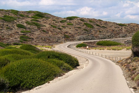 Road with a curve between rocky hills and green shrubsの写真素材