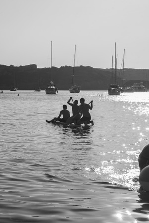 Friends are paddling to the sea to reach their boatの写真素材