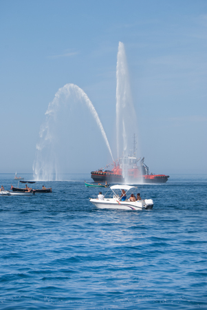Two jets of sea water sprayed by a fire engine of a firefighters red boatの写真素材