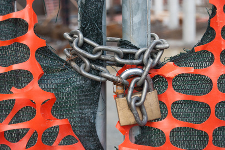 Padlock on a metal gate and plastic nets in an area of under constructionの写真素材