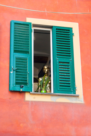 A woman's golden mannequin looks out of a windowの写真素材