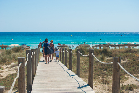 Family walking on a wooden walkway on the sandの写真素材