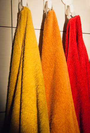 3 orange and red yellow towelshanging on the white wallの写真素材