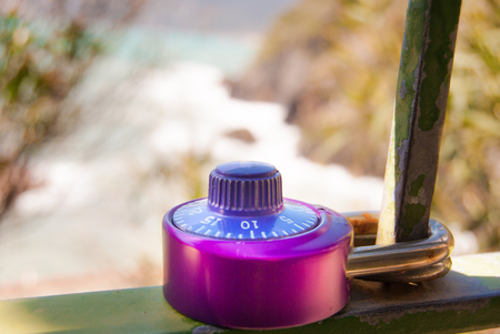 A colored padlock with the numerical combination closed to an metal bar outdoorの写真素材