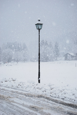 Black streetlight turned off under a spectacular day of falling snowの写真素材