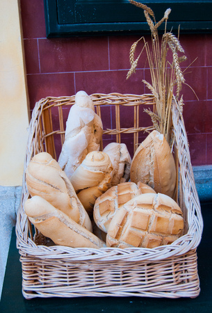 Different type of typical bread withbunch of wheat ears exposed on a table outside a baker shopの写真素材
