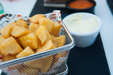 Close-up of fried potatoes with white sauce on the tableの写真素材