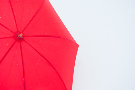 One red umbrella in contrast with the white snowy groundの写真素材