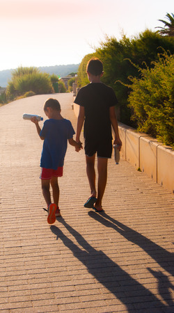 Children walking holding hands and with handmade maracas in the other handsの写真素材