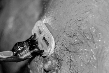 Boy is shaving his chest with a razor bladeの写真素材