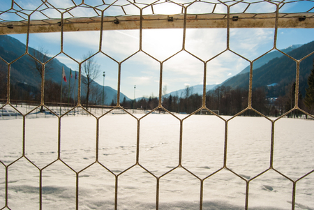 Goal net of a soccer field with snow and panorama on the mountainsの写真素材