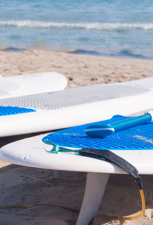 Three surfboards white and blue laid on the beachの写真素材