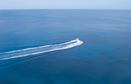 One speedboat going in the middle of the blue and tranquil seaの写真素材