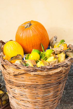 Creative exposition of basket with orange pumpkins yellow melon grapefruits and pears outside of a greengrocerの写真素材