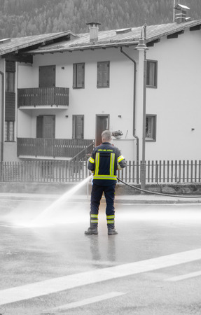 A firefighter with open hydrant in the middle of a streetの写真素材