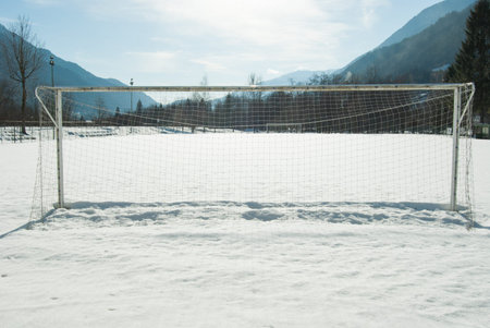 Entire football goal net and snowy field and panorama on the mountains