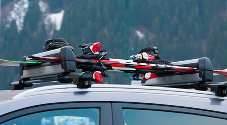 Two pairs of skis and a snowboard on the roof of the carの写真素材