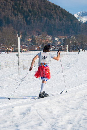 Skier with skirt and swimsuit and competition number during a race in the mountainのeditorial素材