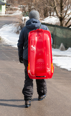 Guy keeping the bobsleigh on the shoulder and walking away on an asphalt streetの写真素材
