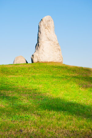 Two grey Menhirs next to each other on green grass with clean and blue skyの写真素材