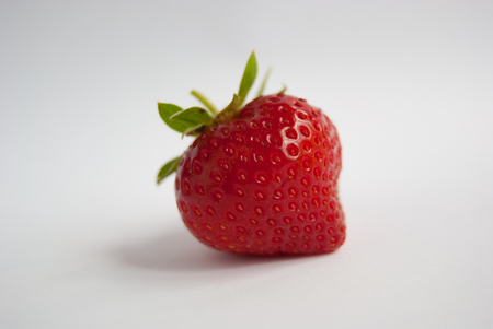 One red strawberry with green leaves on a white backgroundの写真素材
