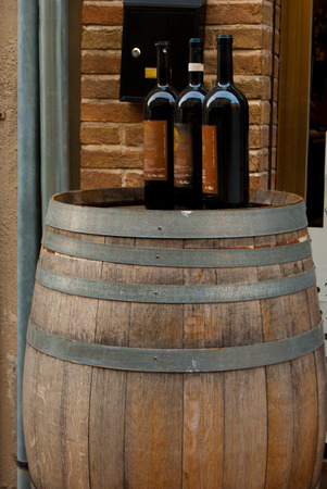 Bottles of italian wine closed over a large barrel used as a tableの写真素材