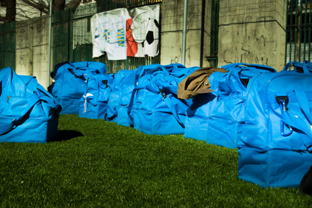A group of light blue sport bags on the green grass of a football fieldの写真素材