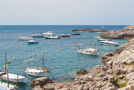 Boats and motorboats moored in a rocky inlet of the Mediterranean seaの写真素材