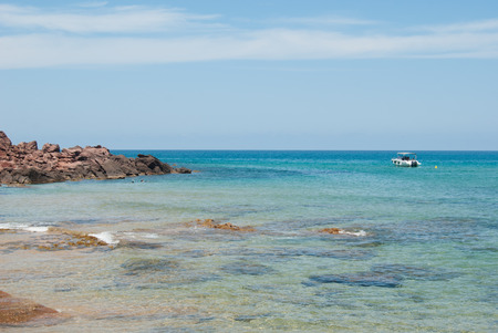 One of the beautiful views of the Spanish island with a small headland and motorboat and a few people snorkelingの写真素材
