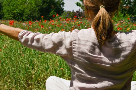 A woman's back while breathing deep in front of a field of flowersの写真素材