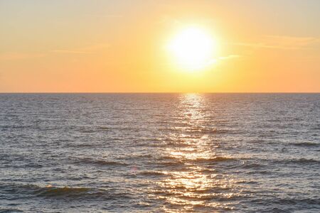Orange and yellow sun  descending with reflection on the seaの写真素材