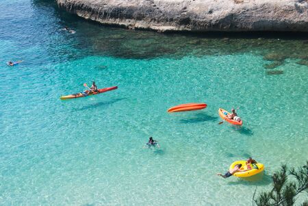 Three kayaks and swimmers in a heavenly turquoise seaの写真素材