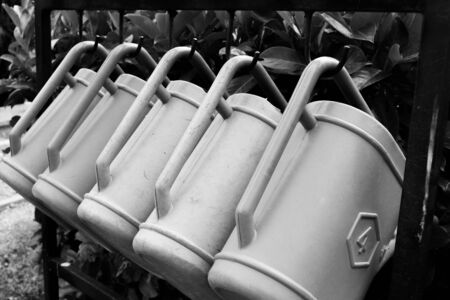 Five watering cans side by side hanging from the cemeteryの写真素材