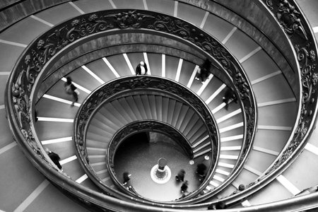 Black and white of impressive ellipticals staircases with few tourists from the Musei Vaticani in...