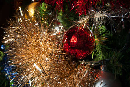 Close-up of a reflective golden ribbon and a bright little red ball two Christmas decorations of the Christmas treeの写真素材