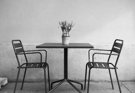 Two chairs and a table with daffosils on it outside an Italian restaurant - center of Milanの写真素材