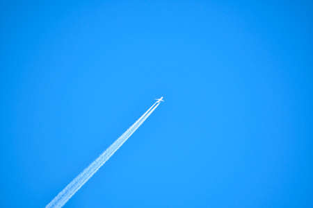 White plane and cloudless blue sky drawing an oblique white lineの写真素材