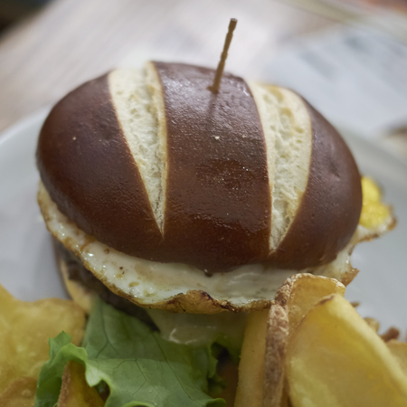 Pretzel sandwich with fried eggs and friesの写真素材