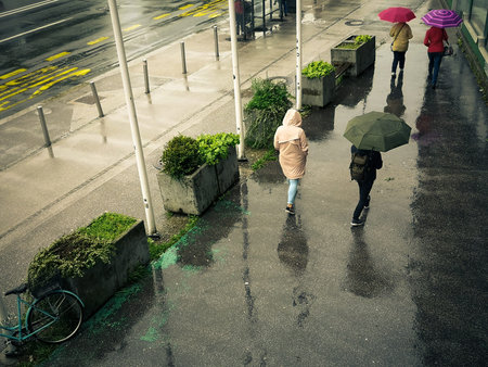 women walk with an umbrella on a rainy, wet street. colorful umbrella
