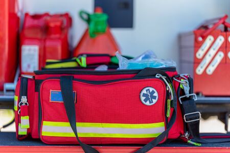 First aid kit an open  red first aid kit bag with a black zip and handle, in closeup. and handle in closeup in an open fire truckの写真素材