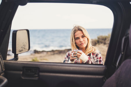 freedom and vacation concept for beautiful blonde caucasian young woman outsidef of a off road black...