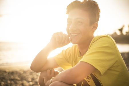 blonde and beautiful teenager 14 years old with sunflare and sunset in the background in Tenerife Canary Islands. young model enjoy the freedom and the beachの写真素材