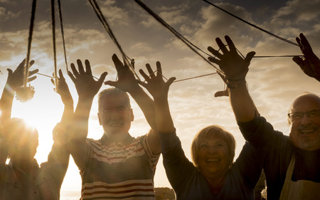 work and have fun together outdoor concept. leisure activity during dinner in the evening with sunset in background. happy day of vacation for senior men and womenの写真素材