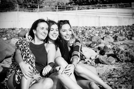 Group of beautiful woman young speaking and smiling aroud in a stone beach in Tenerife. team girls having fun togetherの写真素材