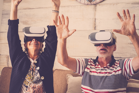 Old senior man and woman using both VR headset white. Playing games experience with eyeglass. Computer technolgy for elderlyの写真素材